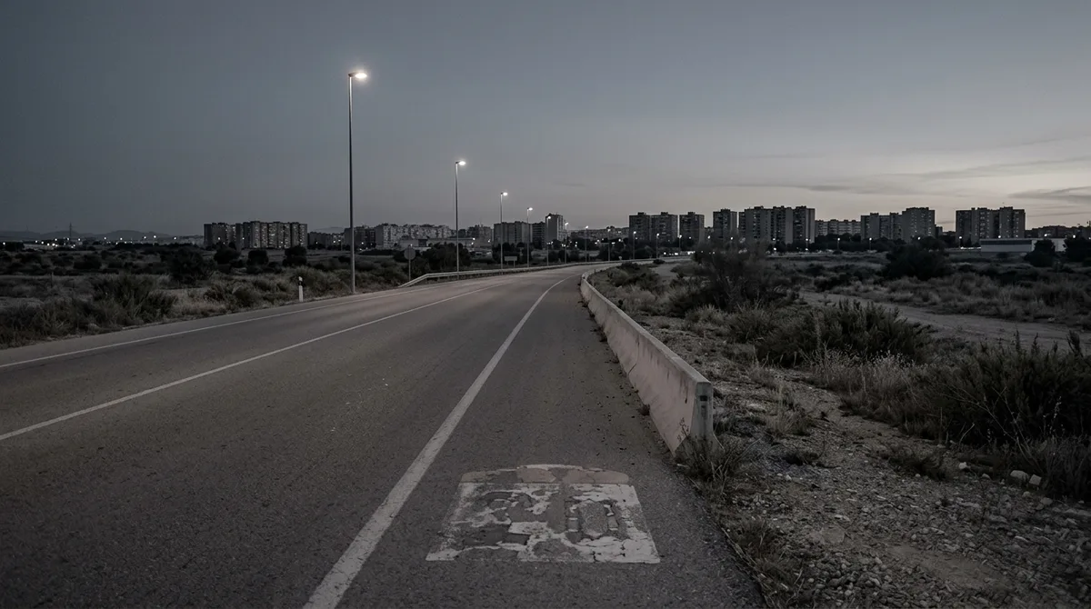 A road marker beside an empty highway at dawn with hills behind